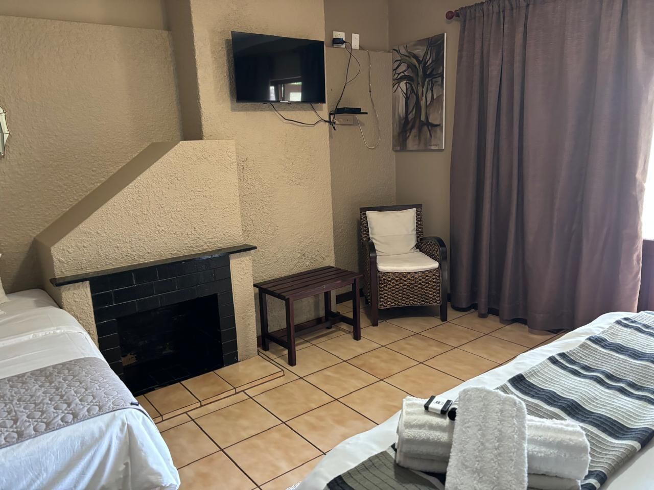Quarto de hotel com lareira, televisão, poltrona e cama.