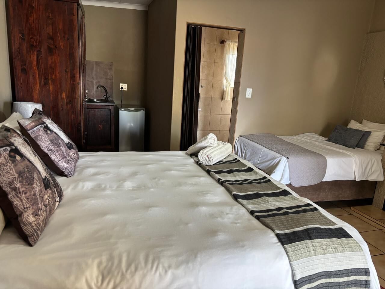 Een hotelkamer met een groot bed, een kleiner bed, een kledingkast, een bureau en een badkamer.