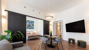 Un salon moderne comprenant un canapé, une table à manger avec des chaises, un lit et un téléviseur fixé au mur.