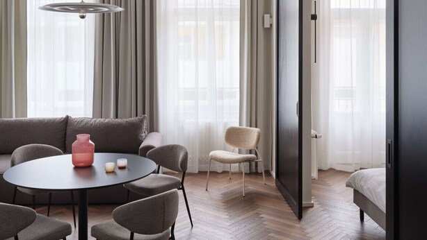 Un salon moderne avec une table ronde, des chaises, un canapé et une grande porte coulissante.