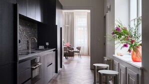 Une cuisine moderne avec des meubles de couleur sombre, un pare-feu en marbre et un plancher en bois disposé en motif chevrons.
