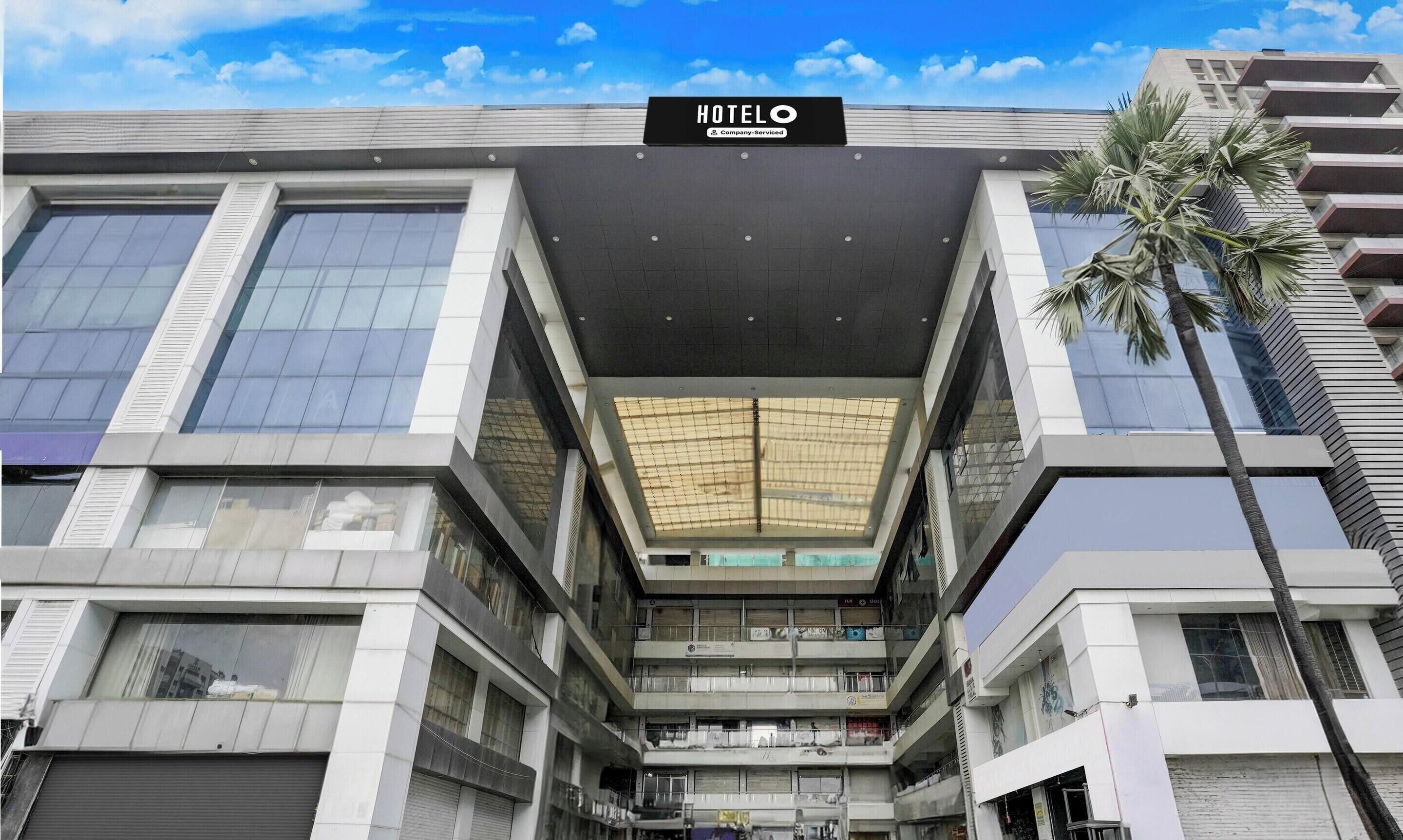 Een modern hotel met een opvallend 'HOTELO' bord, grote ramen en een centraal atrium.