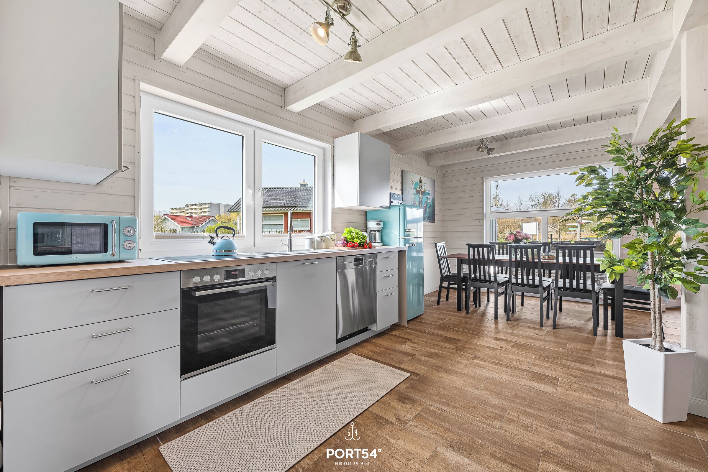 A modern kitchen with white cabinetry, stainless steel appliances, and a large window.