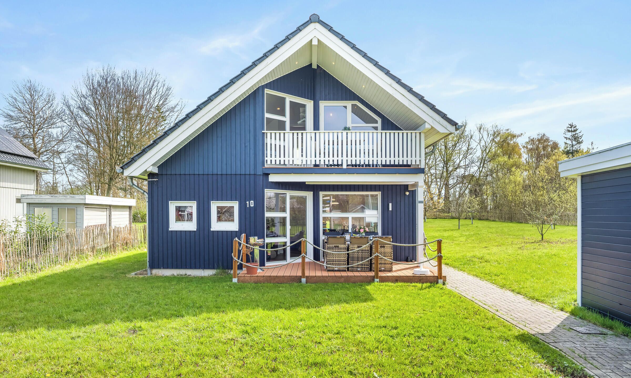 A two-story house with a balcony, a front porch, and a small deck area.