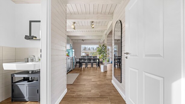 Une cuisine moderne avec un plancher en bois, un coin repas comprenant une table et des chaises, et un grand miroir accroché au mur.