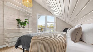 Une chambre à coucher avec un lit, un luminaire suspendu, une fenêtre et une plante.