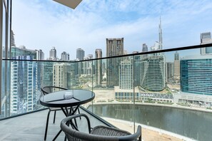 A balcony with a view of a city skyline, including a tall building and a marina. - Stunning Canal View, Studio with Balcony - Peninsula Three, Business Bay (Dubai)