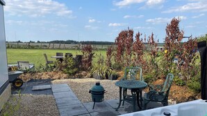 Un patio con un jacuzzi, mobiliario exterior y vistas al campo.