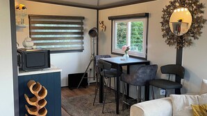 Un espacio habitable compacto con kitchenette, comedor y sala de estar con sofá y sillas.