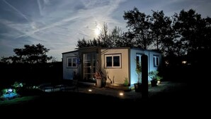 Una casa pequeña y moderna con tejado plano, ventanas amplias y una puerta.