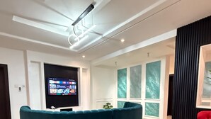 Un vestíbulo moderno con una zona de estar azulada y curva, un televisor de pantalla plana y un ventanal con vistas.
