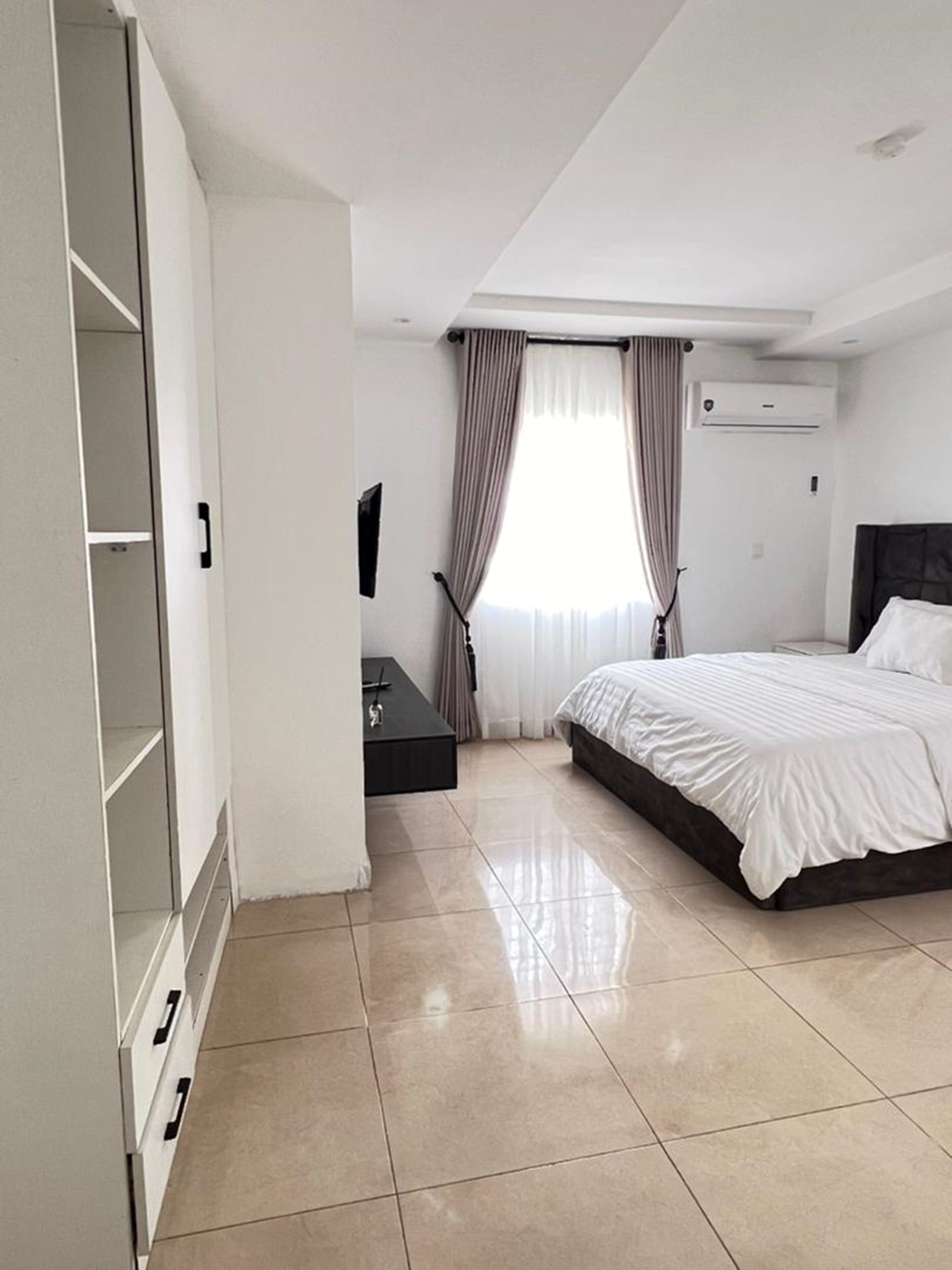A bedroom with a bed, a wardrobe, a desk, and a TV.