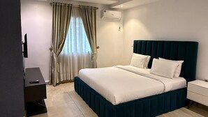 Una habitación de hotel moderna con cama, mesitas de noche, aire acondicionado y televisión.