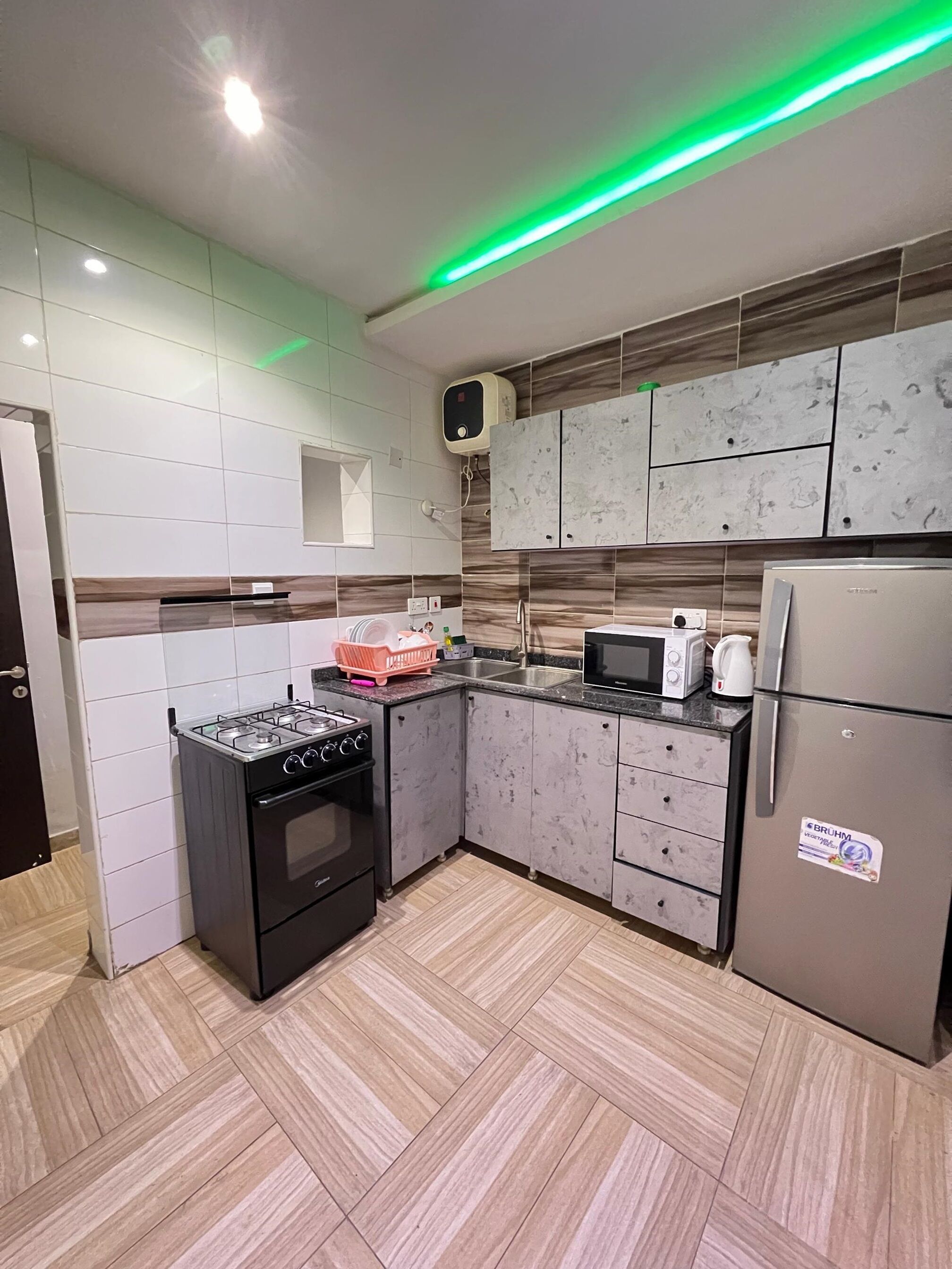A modern kitchen with a gas stove, microwave, refrigerator, and a small sink.