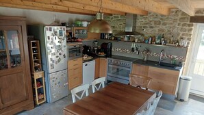 Eine Küche mit Holzausstattung, einem Kühlschrank, einem Herd und einem Esstisch mit Stühlen.