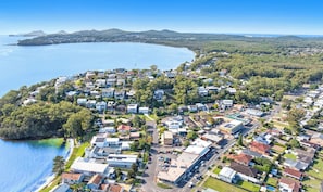 Ett flygbildsfoto av ett bostadsområde vid kusten med hus, vägar och en stor vattenyta.