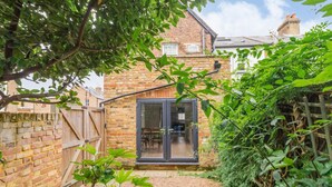 A brick house with a glass door leading to a patio area. - Delightful 2 Bedroom House Central Windsor. Walk to Castle, River! (Windsor)