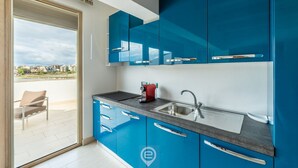 Een moderne keuken met blauwe kastjes, een roestvrijstalen spoelbak en een rode waterkoker.