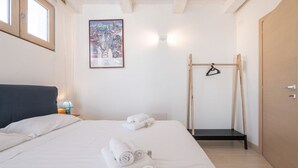 Een slaapkamer met een bed, handdoeken, een schilderij, een houten schommel en een deur.