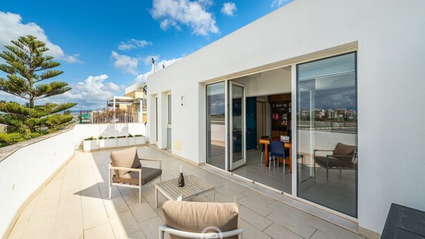 Een modern appartement met een terras, schuiframen en uitzicht over de stad.