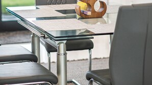 A modern meeting room with a glass table, metal chairs, and a decorative wooden piece. - Nick House (Lehigh Acres)