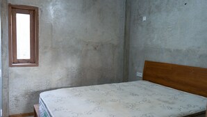 A room with a single bed, a window, and plain walls. - Monkey Palms (Gili Air)