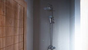 A shower with a handheld showerhead and a wall-mounted faucet, a wooden door, and tiled walls. - Monkey Palms (Gili Air)