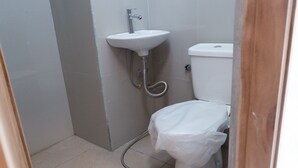A small bathroom with a white sink, toilet, and shower. - Monkey Palms (Gili Air)