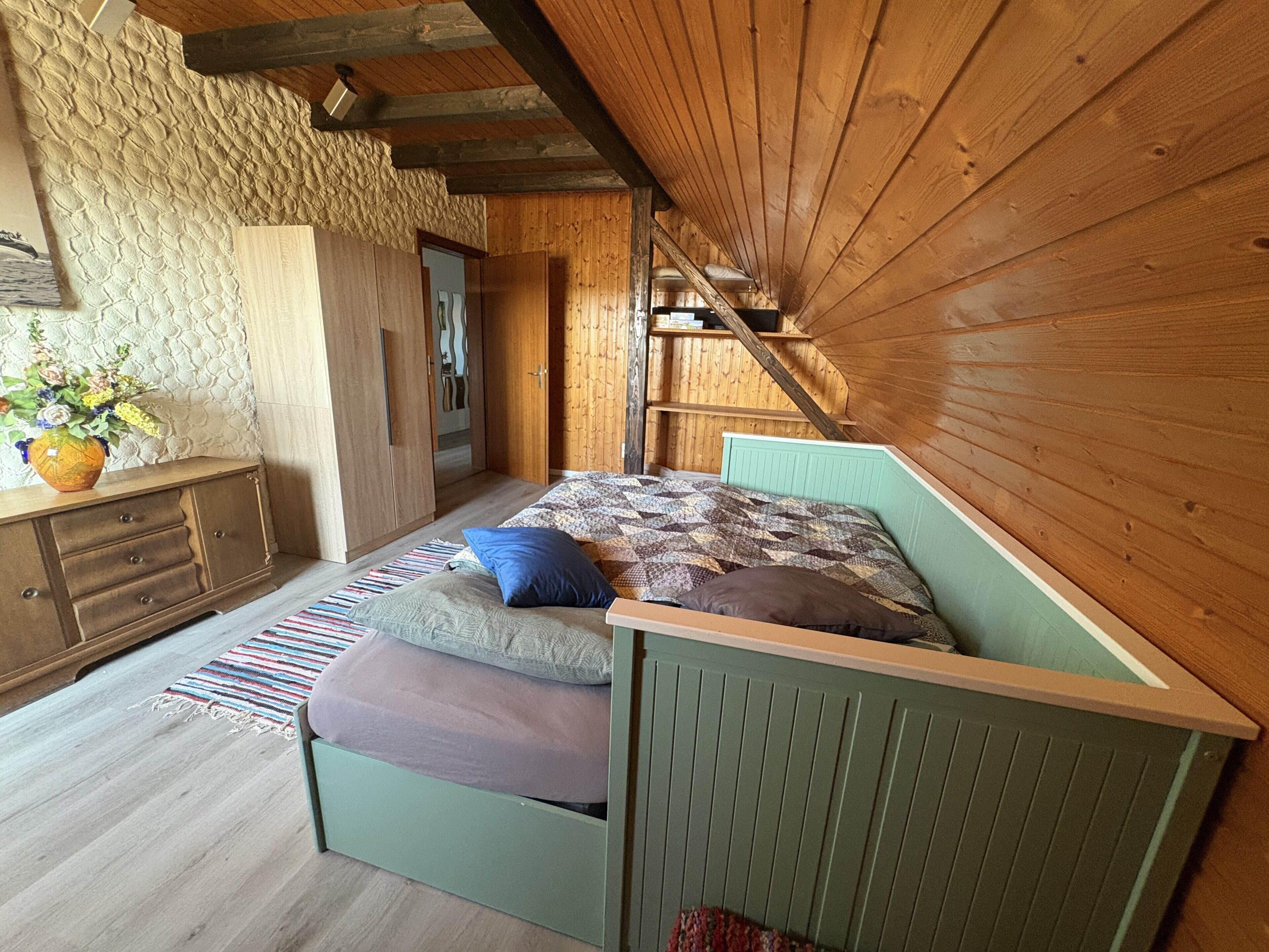 A room with a bed, a dresser, and a wooden wall.