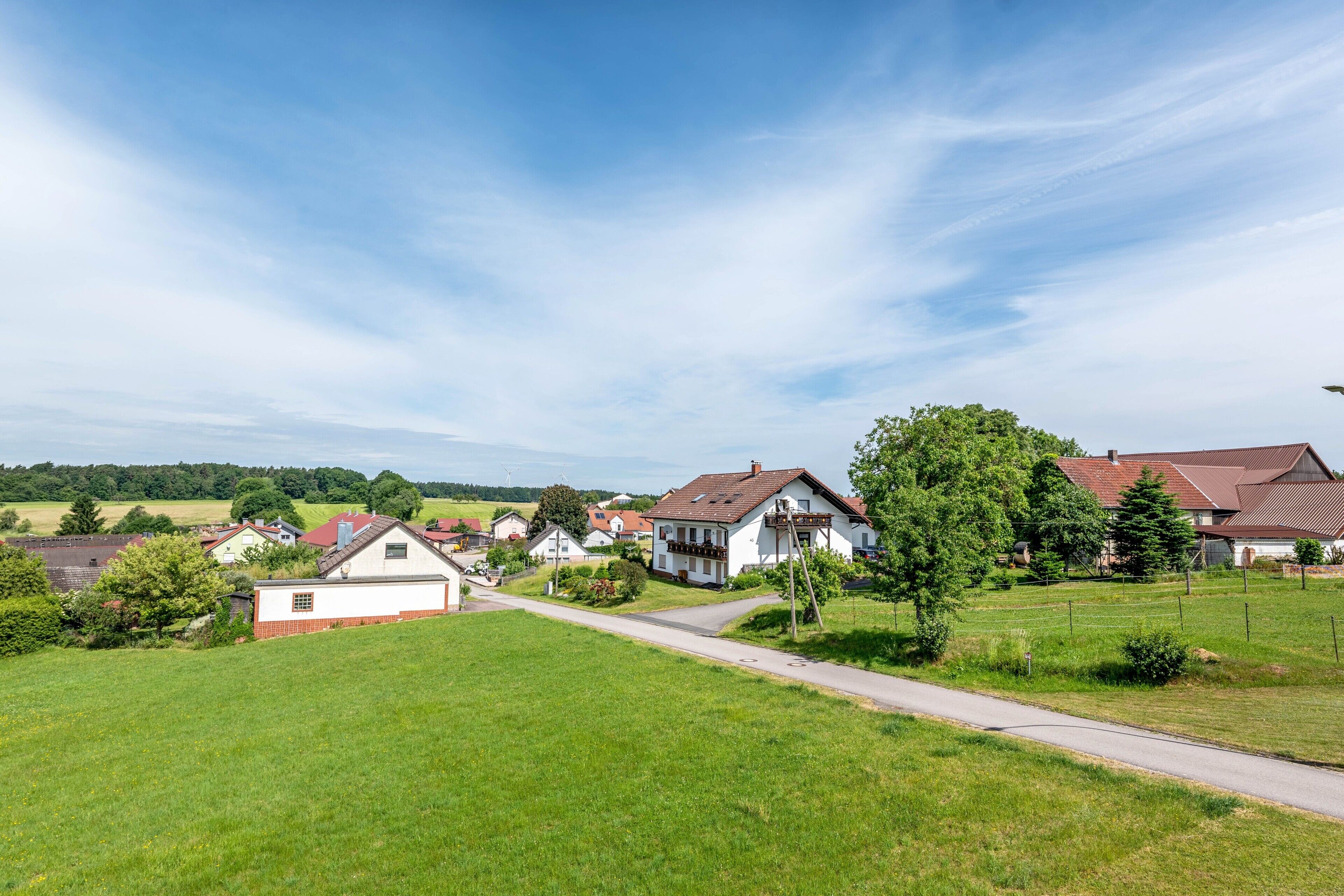 Un village rural avec des maisons, une route et des champs verdoyants.