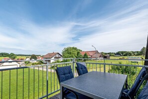 A balcony with a table and chairs, overlooking a green landscape with houses and a clear sky. - Apartment "Haus Schönblick" with Spacious Balcony in the Bavarian Odenwald (Amorbach)