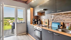 Une cuisine moderne avec des armoires grises, un comptoir en bois, un pare-feu en pierre et une vue sur l’extérieur.
