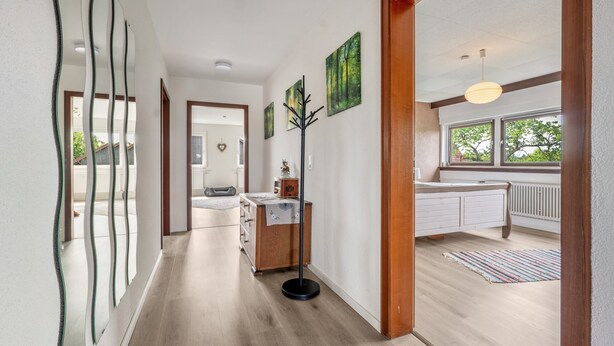 Un couloir avec un plancher en bois, un porte-manteau et un radiateur.