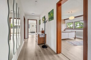 A hallway with a wooden floor, a coat rack, and a radiator.