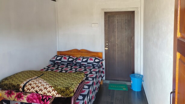 A bedroom with a bed, a door, and a welcome mat.
