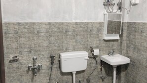 A bathroom with a toilet, bidet, sink, and shower unit.
