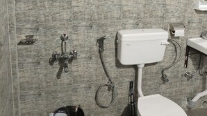 A bathroom with a toilet, shower, and sink.
