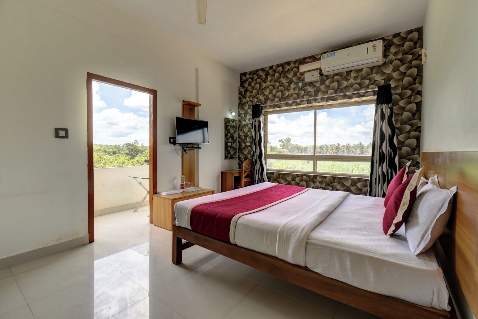A bedroom with a bed, a TV, a stone wall, and a window.
