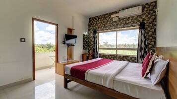 A bedroom with a bed, a TV, a stone wall, and a window.