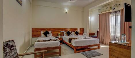 A hotel room with two wooden beds, a ceiling fan, a TV, and a desk with a mirror.