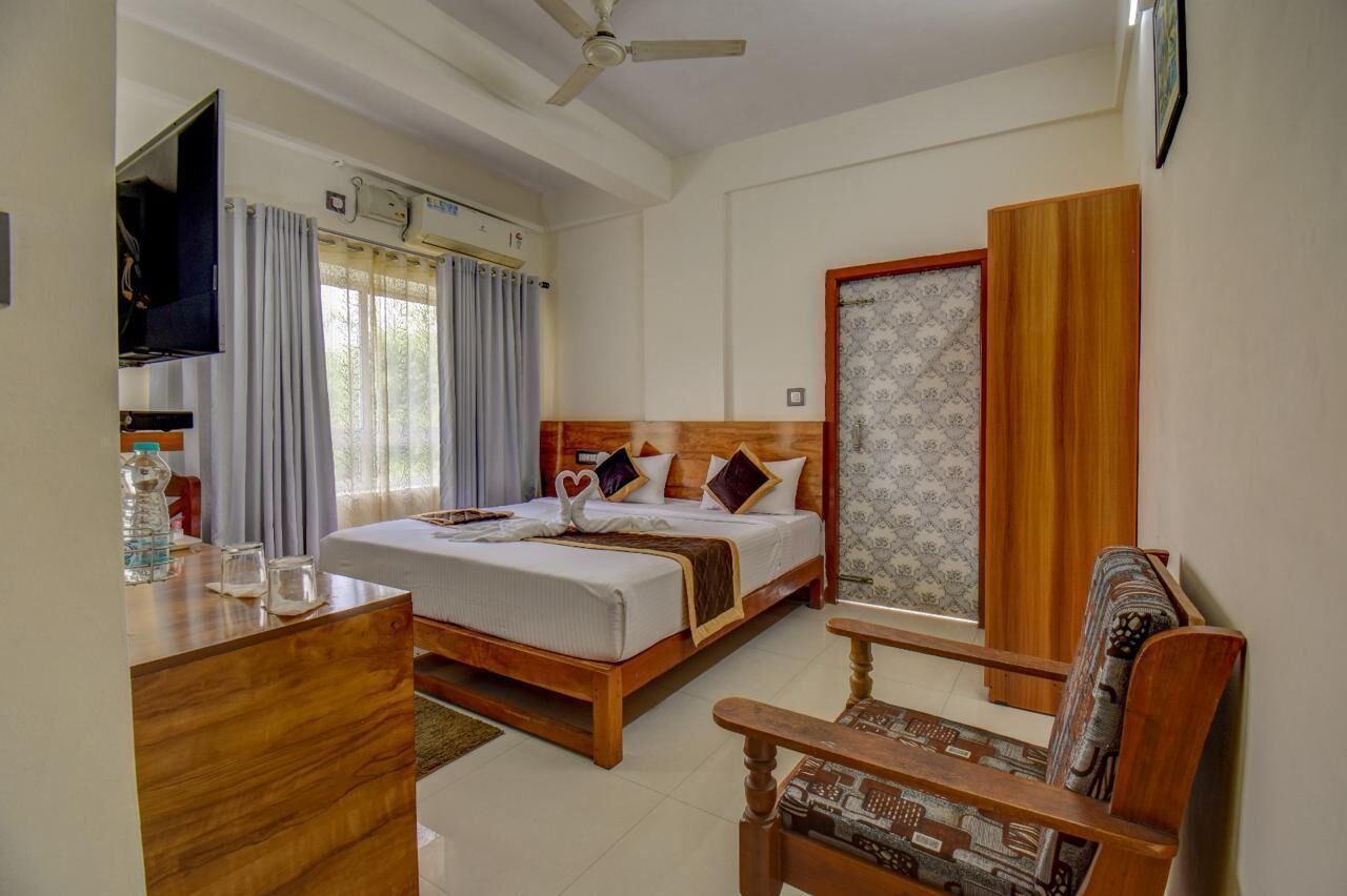 A hotel room with a bed, a desk, a chair, a TV, and a window with curtains.
