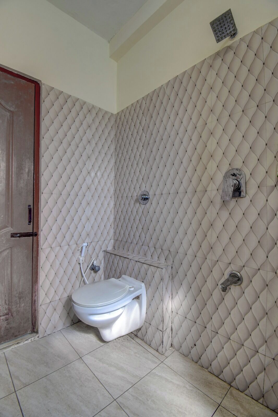 A bathroom with a white toilet, a shower, and a tiled floor.