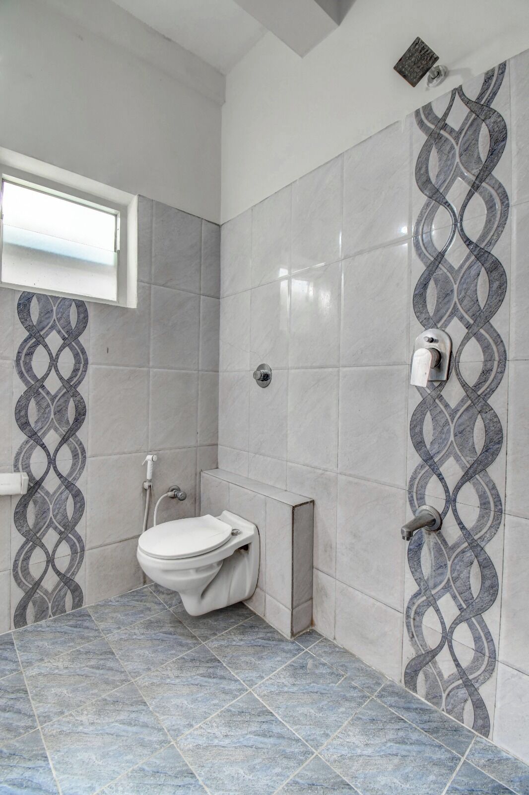 A bathroom with a toilet, a shower, and a patterned wall design.