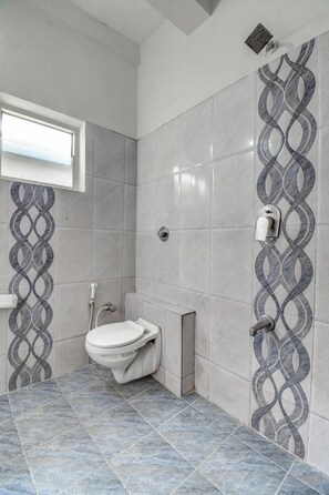 Een badkamer met toilet, douche en een decoratief behang.