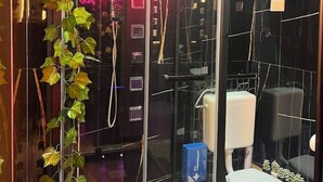 Ein modernes Badezimmer mit Glasabtrennung, Toilette, Dusche und großem Boiler.