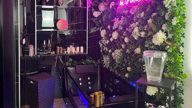 Ein modernes Interieur mit einer Neonreklame, einem Spiegel und einer mit Blumen verzierten Wand.