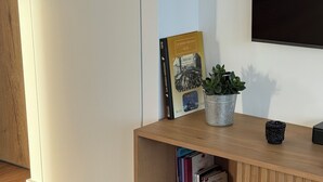 A modern living room with a wooden entertainment unit, a glass coffee table, and a striped rug. - Apartment with terrace – Close to the sea and Royan city center (Royan)