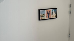 A staircase with a handrail, a white wall, and a framed picture with illustrations. - Apartment with terrace – Close to the sea and Royan city center (Royan)