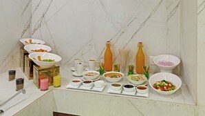A buffet table with various dishes and beverages, set against a marble wall. - Click Collection Aster Jaipur  Raja Park (Jaipur)