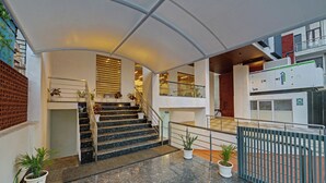 A modern hotel lobby with a marble staircase, potted plants, and a glass railing. - Click Collection Aster Jaipur  Raja Park (Jaipur)